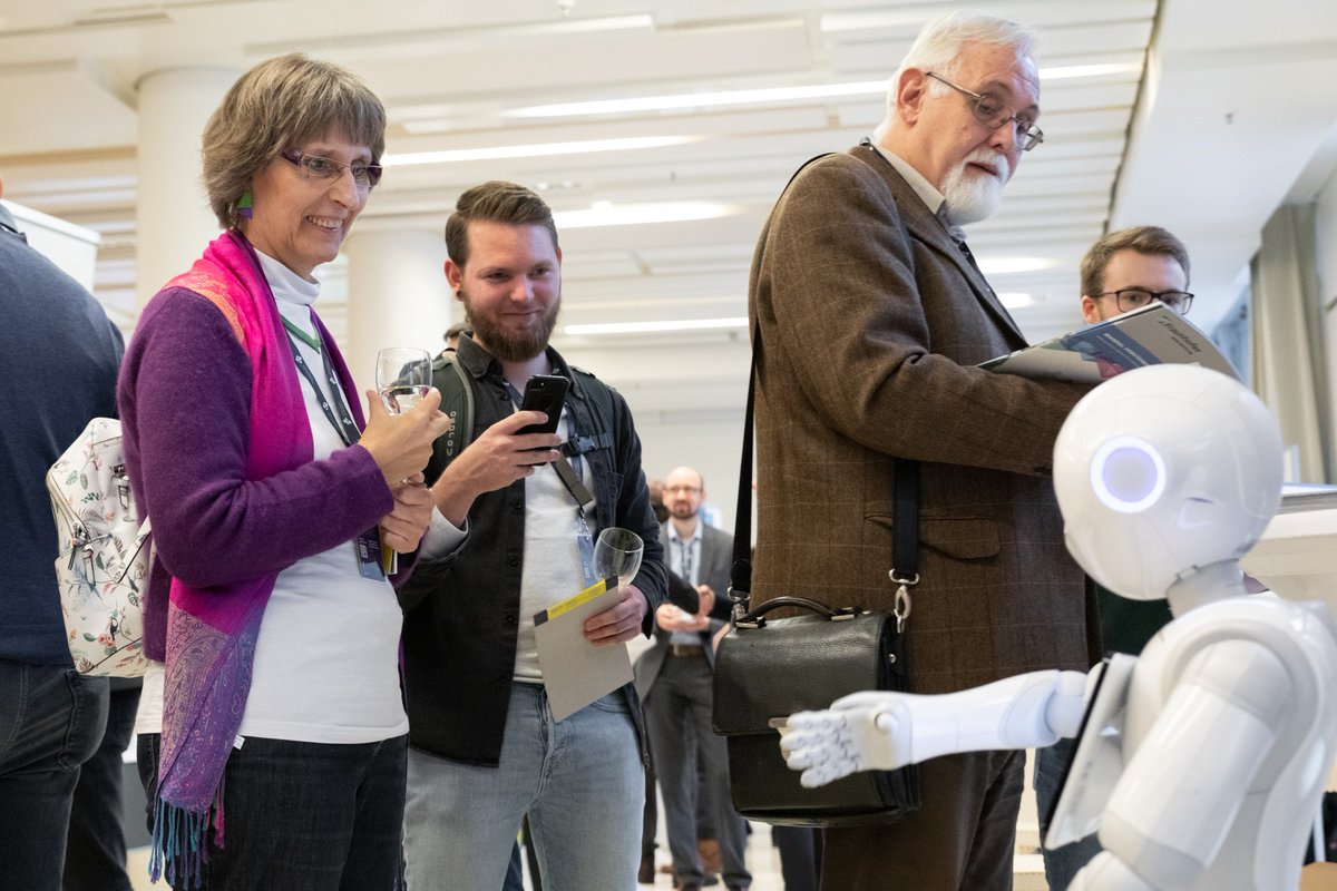 Frau betrachtet lächelnd den kleinen Roboter 